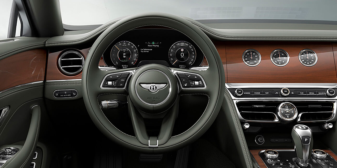 Bentley Bahrain New Bentley Flying Spur sedan front cabin in Cumbrian Green hide and Crown Cut walnut veneer showing steering wheel and Rotating Display with three clocks on face