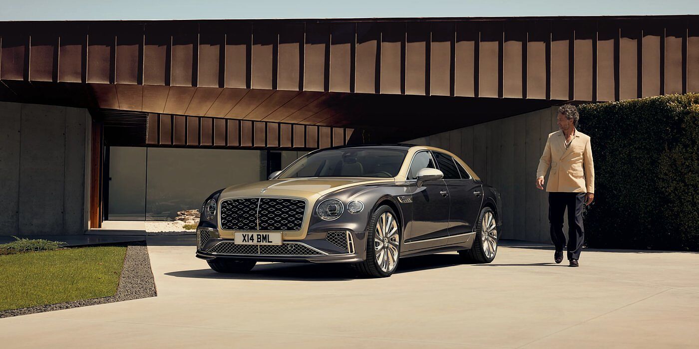 Bentley Bahrain Bentley New Flying Spur Mulliner V8 hybrid sedan front three quarters in Rose Gold over Magnetic paint, parked near modern home