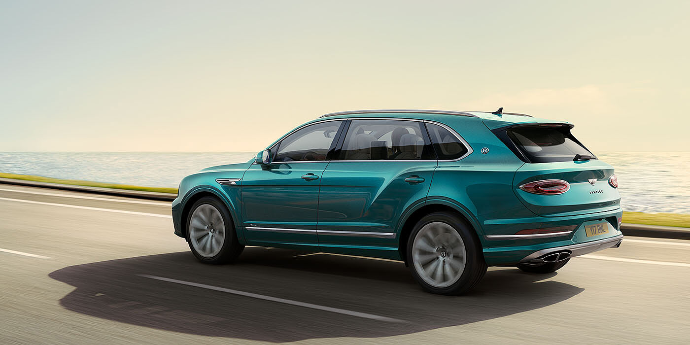 Bentley Bahrain Bentley Bentayga Extended Wheelbase Azure luxury SUV rear three quarter in Topaz Blue by Mulliner paint, driving on an ocean road.