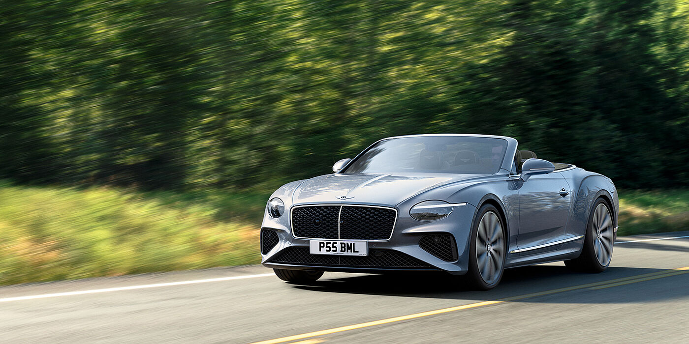 Bentley Bahrain New Bentley Continental GTC convertible front view in Silverlake paint with 22 inch ten spoke wheels, driving dynamically on a country road